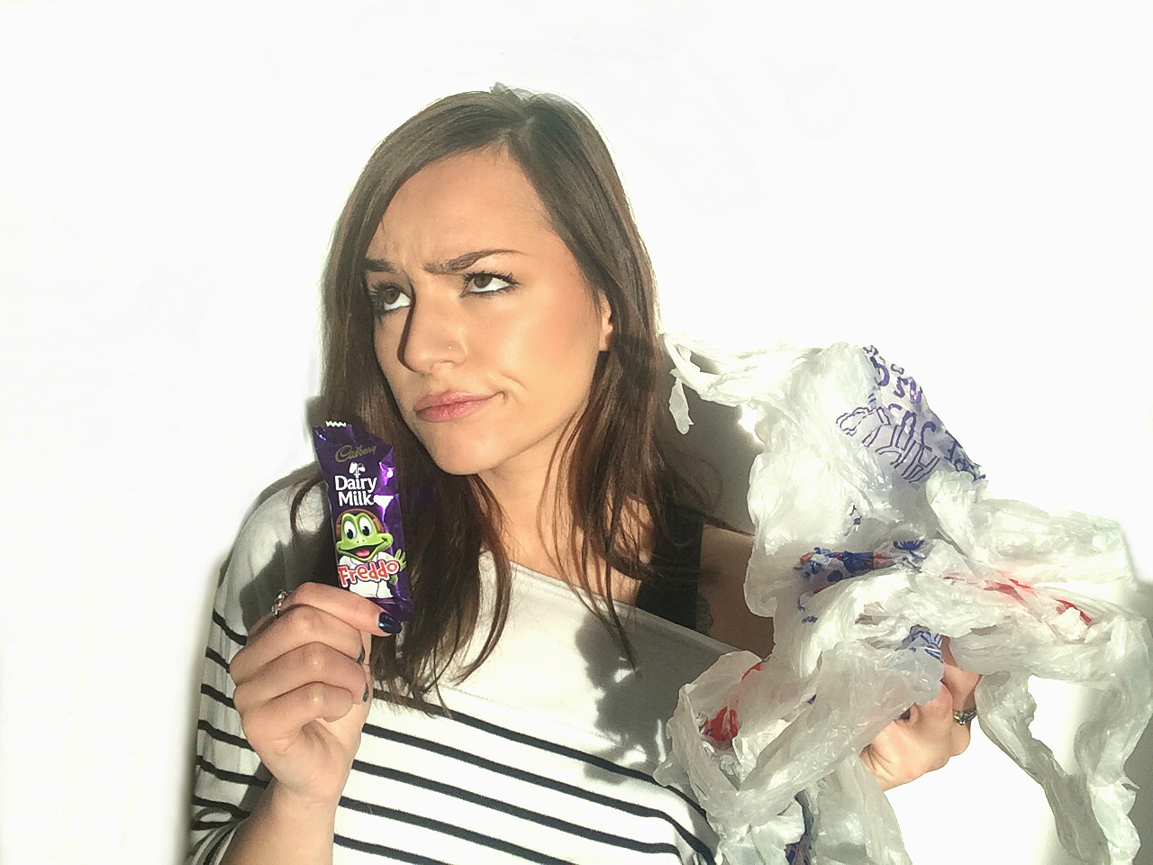 Dani D'silvez from Leafeco holding a Freddo chocolate bar and plastic bags in the other. Explaining that we are treating the 5p plastic bag charge like how we did with the increase in Freddos.