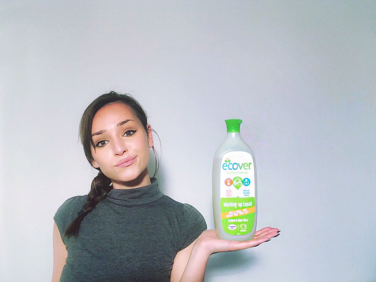 A bottle of Ecover washing up liquid help by a women wearing a grey t-shirt.